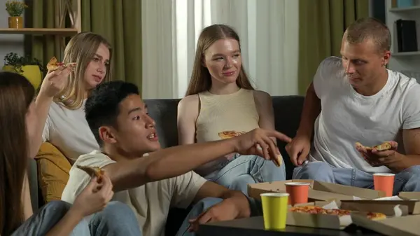 一组青少年 年轻人 坐在沙发上和桌子周围地板上的朋友 吃披萨 喝饮料 开玩笑 — 图库照片