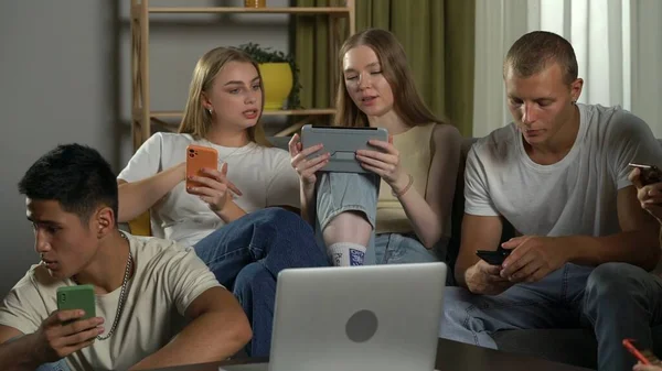 一组青少年 年轻人 坐在沙发上和桌子周围地板上的朋友 用他们的智能手机 笔记本电脑 平板电脑 Gen 现代社会 — 图库照片