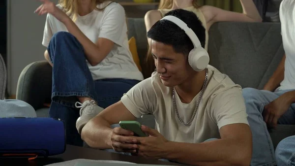 Shot of a boy, guy, sitting in a group of teens, young people, listening to music, scrolling through, surfing the Internet, social media, feed. Advertisement, musical platforms, youth, teenager.