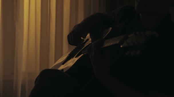 Closeup拍摄了坐在客厅里的年轻人 在音响吉他上弹奏着动听的歌曲 黑暗的公寓里的男性肖像 日常生活创意的概念 — 图库视频影像