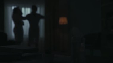 Günlük yaratıcı yaşam konsepti. Masadaki sallanan su bardağına odaklan. Arka plandaki adam ve kadın gece komşulardan gelen bir sesten rahatsız olmuş, telefonla birini aramış..