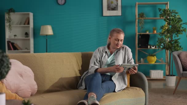 Membuat Kejutan Seorang Wanita Duduk Sofa Dengan Tablet Tangannya Seorang — Stok Video