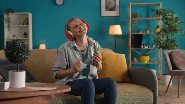 Kırmızı Kablosuz Kulaklık Takan Bir Kadın Akıllı Telefonundan Müzik Dinliyor — Stok fotoğraf