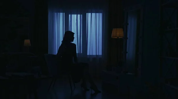 暗いアパートの女性のシルエットの肖像画 日常生活のクリエイティブコンセプト ドレスとハイヒールを着た女性が部屋の椅子に座り 鏡の中で自分自身を見つめている — ストック写真