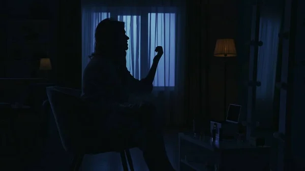 暗いアパートの女性のシルエットの肖像画 日常生活のクリエイティブコンセプト クローズアップショット 部屋の椅子に座っているバスローブの女性 彼女の爪を見て 電話で話す — ストック写真