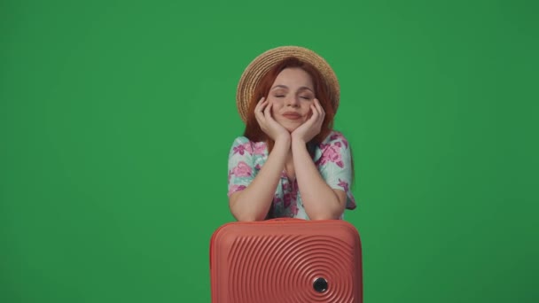 旅行広告クリエイティブコンセプト バケーションを夢見る幸せな笑顔の表情のストロー帽子で女性の旅行者は スーツケースに手を握ります 緑の背景に孤立した — ストック動画