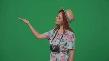 Gezici reklam yaratıcı konsepti. Elleri boş, gülümseyen yüz ifadesi olan bir kadın gezgin. Reklam için yer açın. Yeşil arkaplanda izole.