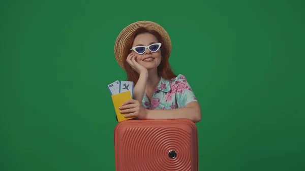 旅行广告创意的概念 戴着草帽和眼镜的女旅客拿着机票 微笑着抬头 梦想着 被绿色背景隔离 — 图库照片