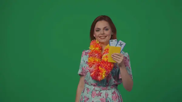 旅行広告クリエイティブコンセプト フライトチケットを持って カメラ 広告代理店を見ている花輪とドレスの女性 緑の背景に孤立した — ストック写真