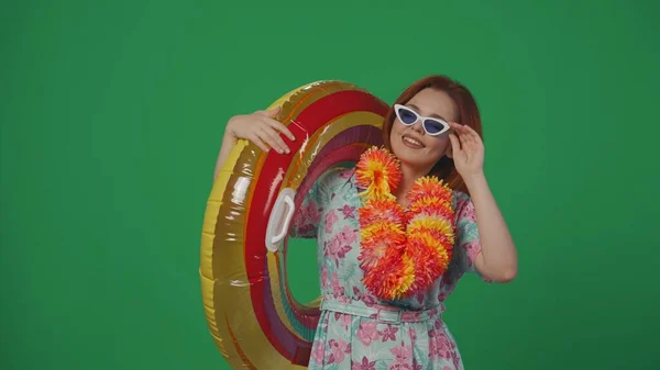 旅行广告创意的概念 戴着眼镜和花环的女旅行者拿着充气管环 一边度假一边摆姿势 一边拍照 被绿色背景隔离 — 图库照片