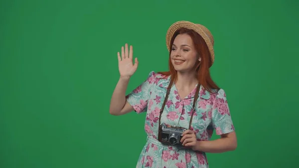 旅行広告クリエイティブコンセプト フィルムカメラでわら帽子をかぶった女性は ハイと言って幸せな顔の手で誰かに挨拶します 緑の背景に孤立した — ストック写真