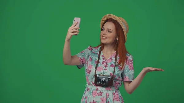 旅行広告クリエイティブコンセプト 女性は ビデオ通話でスマートフォンで話す帽子で旅行し 幸せな顔の表情を示す微笑みます 緑の背景に孤立した — ストック写真