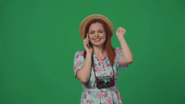 旅行广告创意的概念 头戴草帽的女旅行者在智能手机上与朋友交谈 面带微笑 面带微笑 被绿色背景隔离 — 图库照片