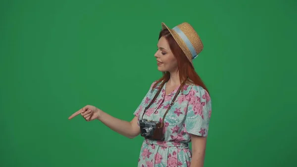 头戴草帽的女旅行者指着空旷的地方 笑容满面 插入广告的空间 被绿色背景隔离 — 图库照片