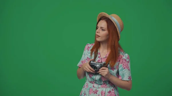 旅行広告クリエイティブコンセプト 古いフィルムカメラでストロー帽子で旅行する女性は アトラクションを見回し 驚いた顔の表情を見ます 緑の背景に孤立した — ストック写真
