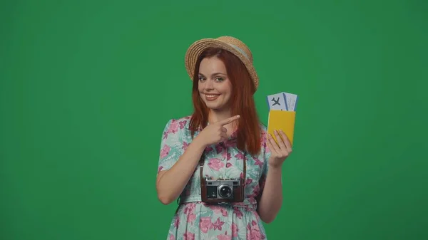 旅行广告创意的概念 头戴草帽的女旅客拿着机票和护照 指着它 满脸喜色 被绿色背景隔离 — 图库照片