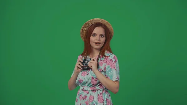 旅行广告创意的概念 头戴草帽的女旅行者拿着旧胶卷摄像头 看着镜头准备拍照 惊讶的脸 被绿色背景隔离 — 图库照片