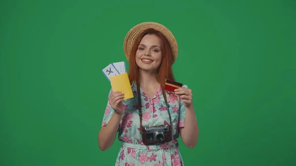 旅行广告创意的概念 头戴草帽的女旅客拿着机票和信用卡 笑容满面 被绿色背景隔离 — 图库照片