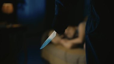 Korku filmi sahnesi. Cadılar Bayramı reklam konsepti. Yakından çekilen kız oturma odasındaki kanepede uyuyor, elinde bıçakla onun önünde duran manyak adama odaklanıyor..