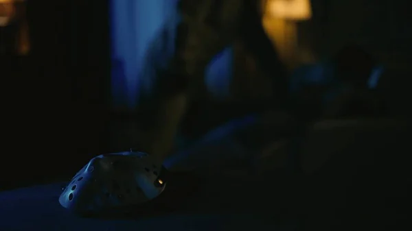 ホラー映画シーン ハロウィン広告コンセプト クローズアップショット ホワイトホッケーマスクに焦点を当て 背中のマニアックとナイフとソファーの犠牲者 — ストック写真