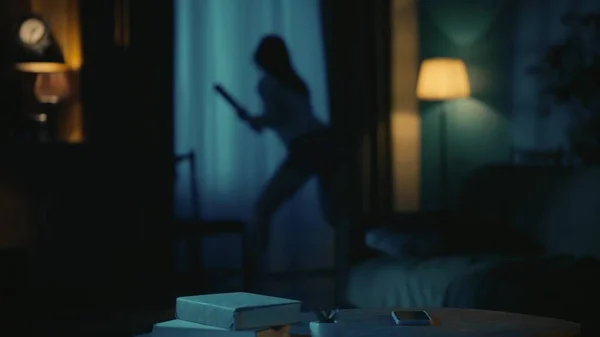 恐怖的电影场景 万圣节广告的概念 害怕年轻姑娘拿着棒球棒站在黑暗的客厅里靠窗的地方 望着外面 — 图库照片