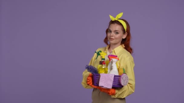清洁和家政创意的概念 身穿休闲装 戴着橡胶手套 提着一篮子清洁工具的女人 手举起来看着相机 被紫色背景隔离 — 图库视频影像