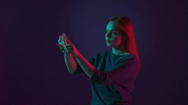 Genç bir kadın görünmez bir dokunmatik ekranda çalışıyor. Stüdyoda pembe ve yeşil neon ışıklı mavi arka planda bir kadın var. Gelecekçi teknoloji