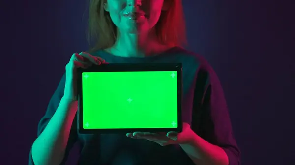 用粉红和绿色霓虹灯把一个有绿色屏风的女用平板放在工作室里 — 图库照片