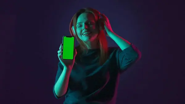 Eine Frau Mit Roten Drahtlosen Kopfhörern Zeigt Einen Grünen Smartphone — Stockfoto