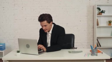 Ofiste çalışan, dizüstü bilgisayarına bakan, başarıya tepki olarak yumruğunu sallayan, harika ya da başarılı bir adamın orta boy videosu. Sonra bir sürü para gösteriyor. Teklif, reklam.