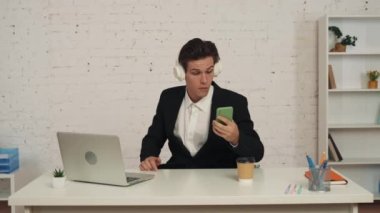 Ofisteki bir gencin orta boy videosu, esneme, kulaklık takması, şarkı çalması, akıllı telefonuyla müzik dinlemesi, kahvesini yudumlaması, dans etmesi. Müzik platformları ve teçhizat, reklam.