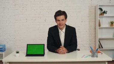 Ofisteki genç bir adamın reklam alanı olan bir tabletle orta boy videosu. Çalışma alanı onu taklit ediyor. Adam ekranı işaret ediyor ve baş parmağını kaldırıyor. İş, web kaynakları, uygulama.