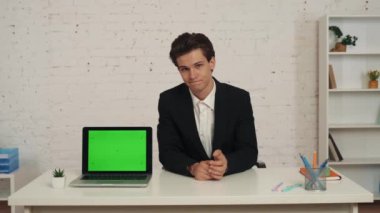 Ofisteki genç bir adamın reklam alanı olan bir dizüstü bilgisayarı olan orta boy videosu. Çalışma alanı onu taklit ediyor. Adam ekranı işaret ediyor ve baş parmağını kaldırıyor. İş, web kaynakları, uygulama.