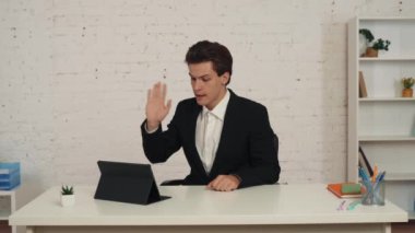 Ofiste, tabletinin önünde oturmuş video aramasını bekleyen genç bir adamın orta boy videosu. Sonra konuşmaya başlıyor, biriyle konuşuyor, tartışıyor ve azarlıyor. İş, web kaynakları, uygulama.