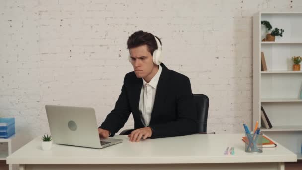 Середнє Відео Молодого Чоловіка Офісі Працює Ноутбуком Слухає Музику Через — стокове відео