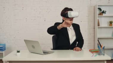 Ofisteki genç bir adamın sanal gerçeklik kaskı, teçhizatı, kaydırma, yakınlaştırma ve mutlu bir şekilde görünmeyen bir ekrana dokunuşunun orta boy videosu. Modern teknoloji, görsel efektler, fırsatlar.