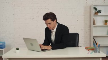 Ofiste çalışan, bilgisayarına bakan, mesaj alan, iyi haberlerle bilgilendirme yapan genç bir adamın orta boy videosu. Sonra tamam işareti, jest gösteriyor. İş fırsatı, reklam..