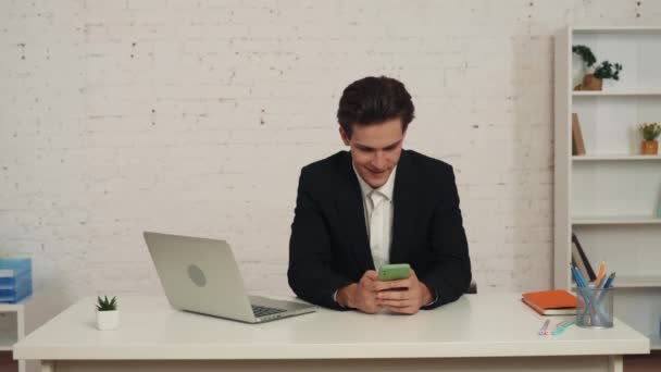 Vídeo Mediano Joven Sentado Oficina Mesa Con Smartphone Las Manos — Vídeo de stock