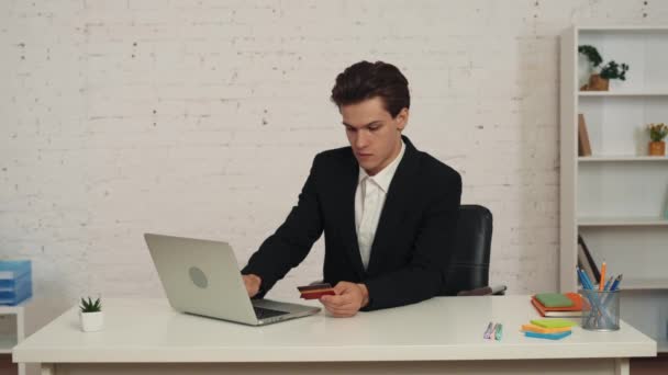 Közepes Videó Egy Fiatalemberről Aki Asztalnál Laptopot Használ Hitelkártyát Tart — Stock videók