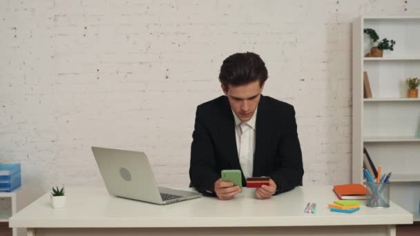 Vídeo Médio Jovem Sentado Mesa Segurando Smartphone Cartão Crédito Completando — Vídeo de Stock