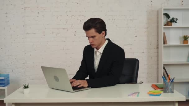 一个年轻人坐在桌旁 在笔记本电脑上工作 在漫长的一天之后按摩他的脖子 然后换班的中等视频 过度工作 健康问题 久坐不动的生活方式 — 图库视频影像