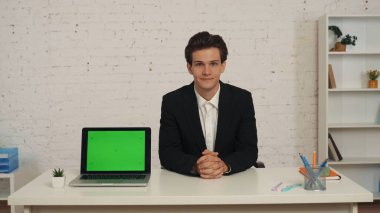 Ofiste genç bir adamın orta boy fotoğrafı, üzerinde reklam alanı olan bir dizüstü bilgisayarla masada oturması, çalışma alanının afiş için hazırlanması, tanıtım içeriği. İş, web kaynakları, uygulama.