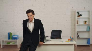 Ofiste genç bir adamın bir mesaj aldıktan sonra masaya eğildiği, kötü haberlerle bilgilendirdiği orta boy bir fotoğraf. Hayal kırıklığıyla, hayal kırıklığıyla tepki veriyor. Başarısız anlaşma, reklam..