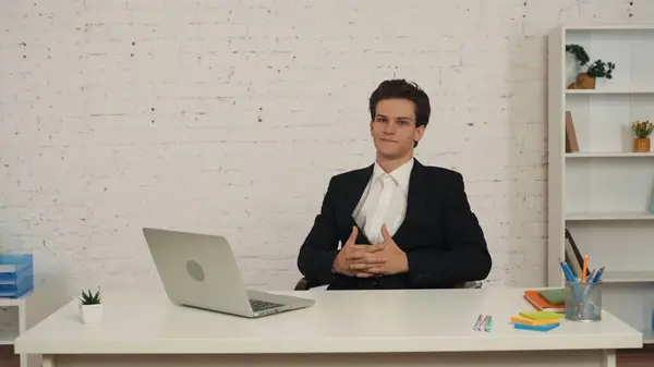 一个年轻人坐在桌旁 手牵着手 双手交叉 双手紧握着 表现出自信和决心 商业广告 经销商 — 图库照片