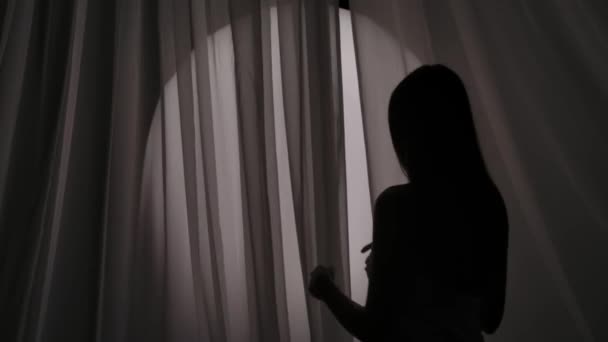 タオルで包まれた若い女性のシルエットのミディアムビデオは カーテンの後ろに隠れて 気遣い マフラッドライトで髪を泳いでいました 製品広告 セルフケアルーチン — ストック動画