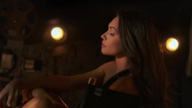 Sinematografi ve sahne arkası yaratıcı konsepti. Yakın çekim, zarif esmer yarı çıplak kadın yönetmen koltuğunda oturuyor, film şeritlerine dolanmış kameraya bakıyor..