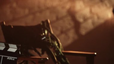 Sinematografi ve sahne arkası yaratıcı konsepti. Film şeritli yönetmen koltuğu. Altın elbiseli kadın, elinde alçıpanla çerçeveye girer tahtayı kapatır ve uzaklaşır..