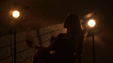 Sinematografi ve sinema sahne arkası reklam yaratıcı konsepti. Güzel bir bayan silueti, yönetmen koltuğunda oturuyor, sigara tutacağı tutuyor ve sigara içiyor..