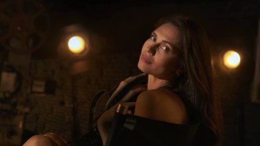 Sinematografi ve sinema sahne arkası reklam yaratıcı konsepti. Film şeritleri içinde esmer bir kadının sahne arkasında yönetmen koltuğunda oturup kameraya baktığı yakın çekim..