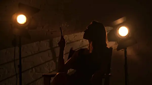 映画と映画の舞台裏広告クリエイティブコンセプト 監督の椅子に座っている黒いドレスの美しい女性のシルエット 優雅にタバコのホルダーと喫煙 — ストック写真
